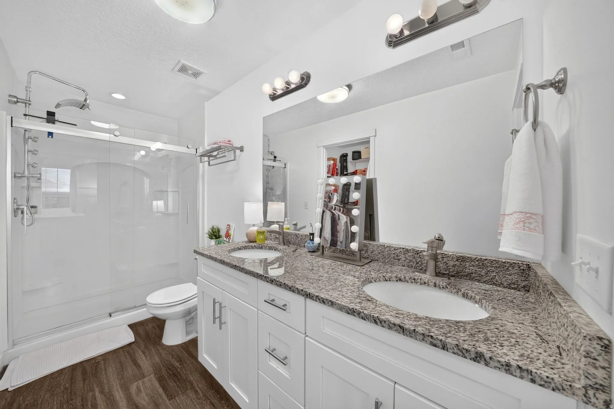 Bathroom featuring a dual vanity with a speckled countertop, undermount sinks, and white shaker cabinetry