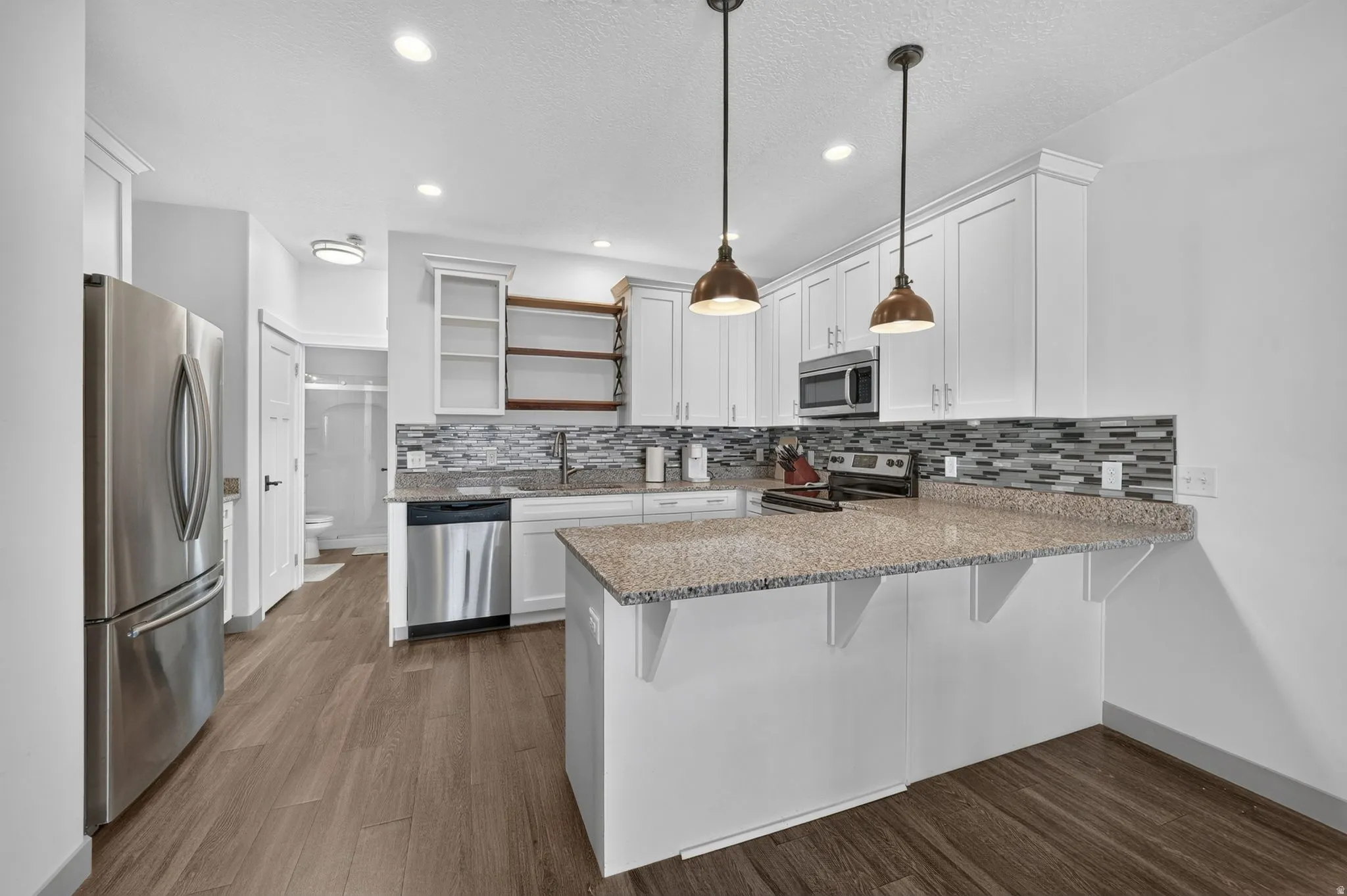 Contemporary kitchen featuring wood-finish flooring, white cabinetry, and stainless steel appliances