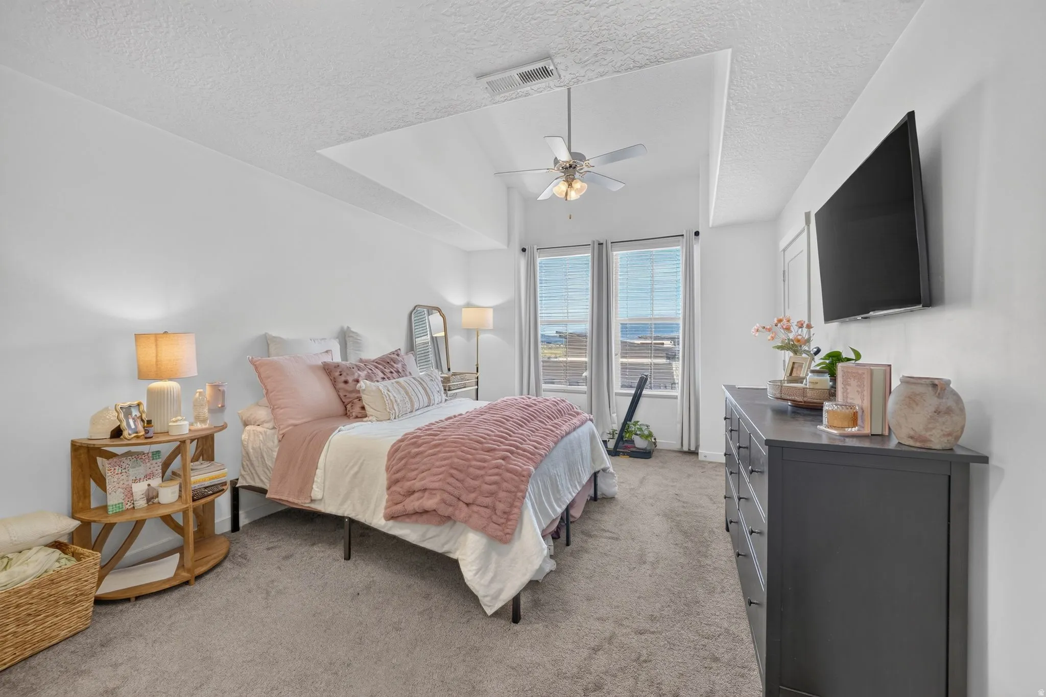 Spacious bedroom featuring a tray ceiling, recessed lighting, and a ceiling fan