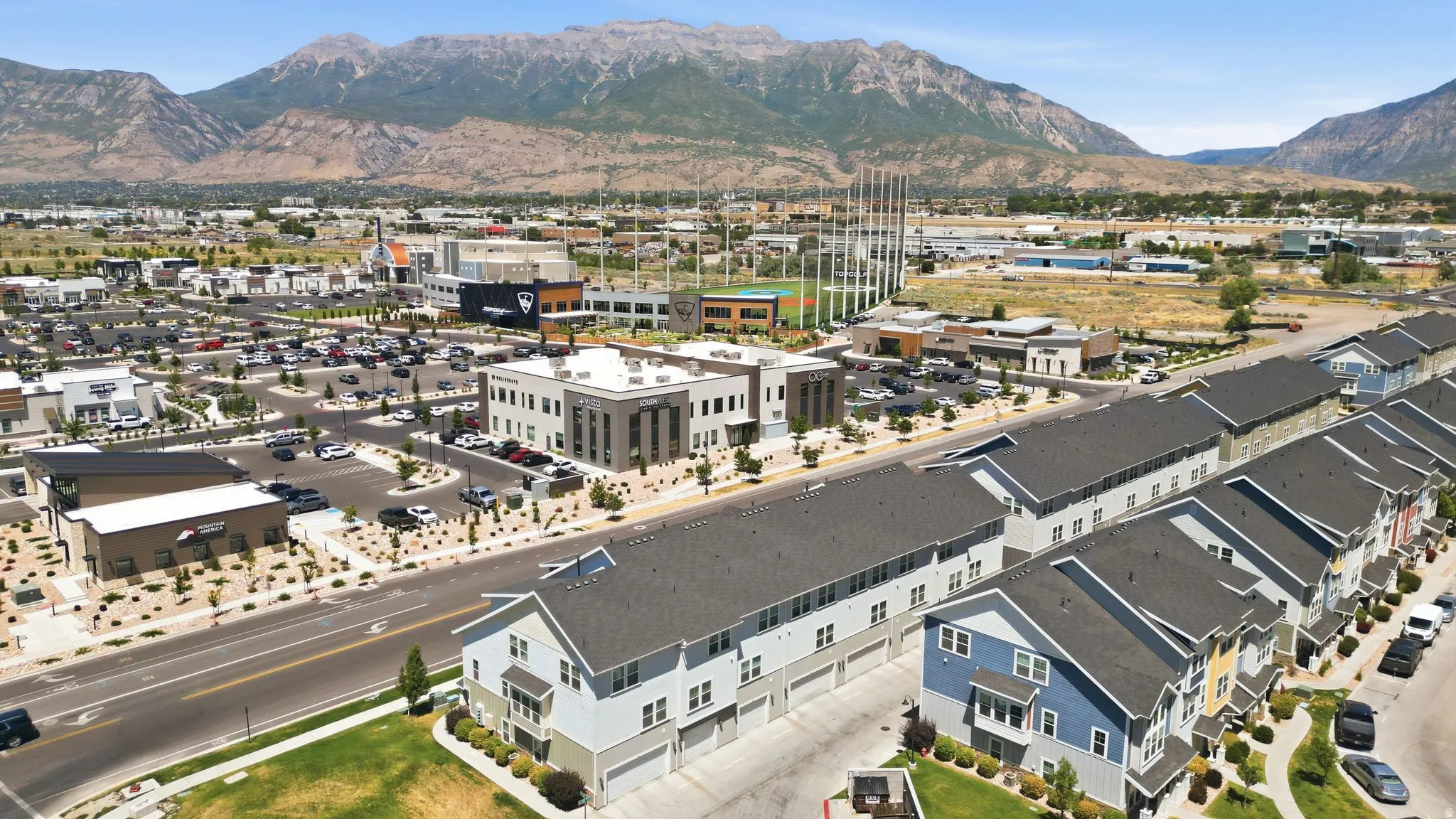 Row of townhomes featuring multi-tone exteriors, individual garages, and dark shingle roofs