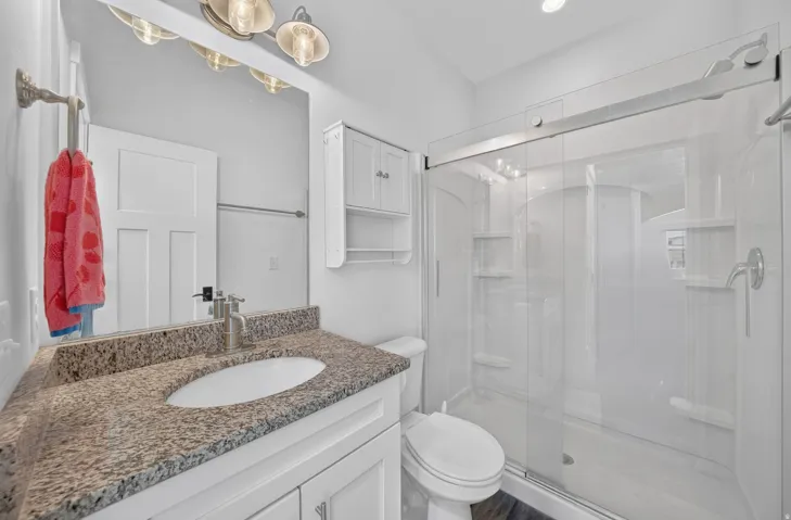 Bathroom featuring a vanity with a granite-finish countertop, undermount sink, and brushed nickel faucet