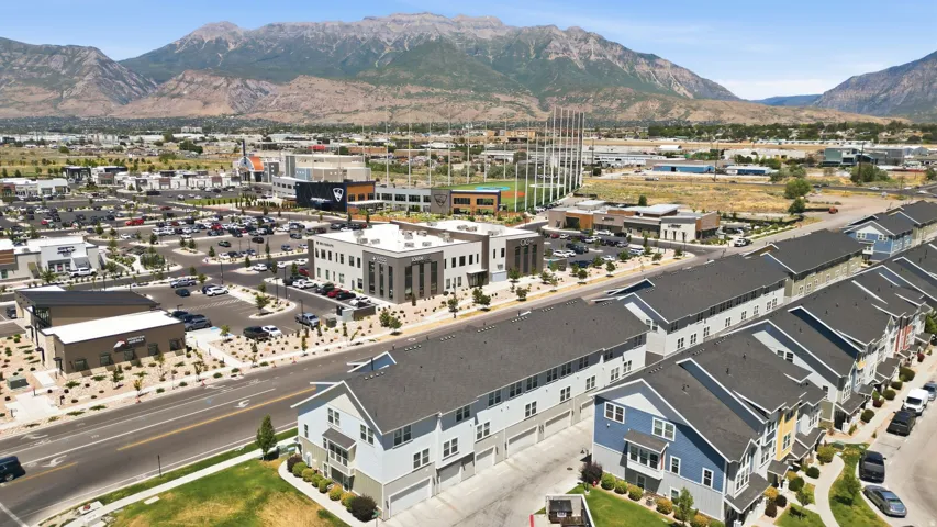 Row of townhomes featuring multi-tone exteriors, individual garages, and dark shingle roofs
