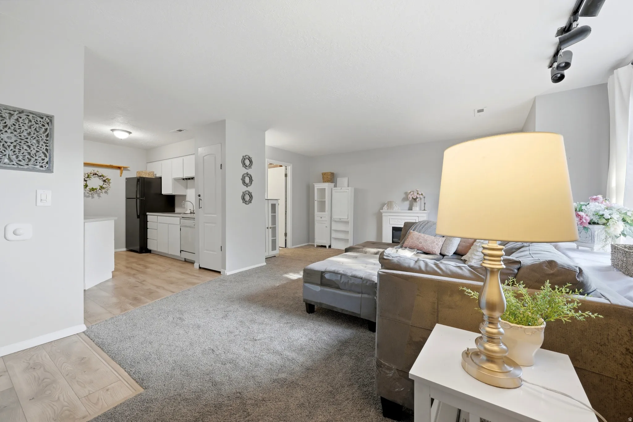 Open-concept living area featuring light gray wall paint, gray carpeting, and wood-finish flooring