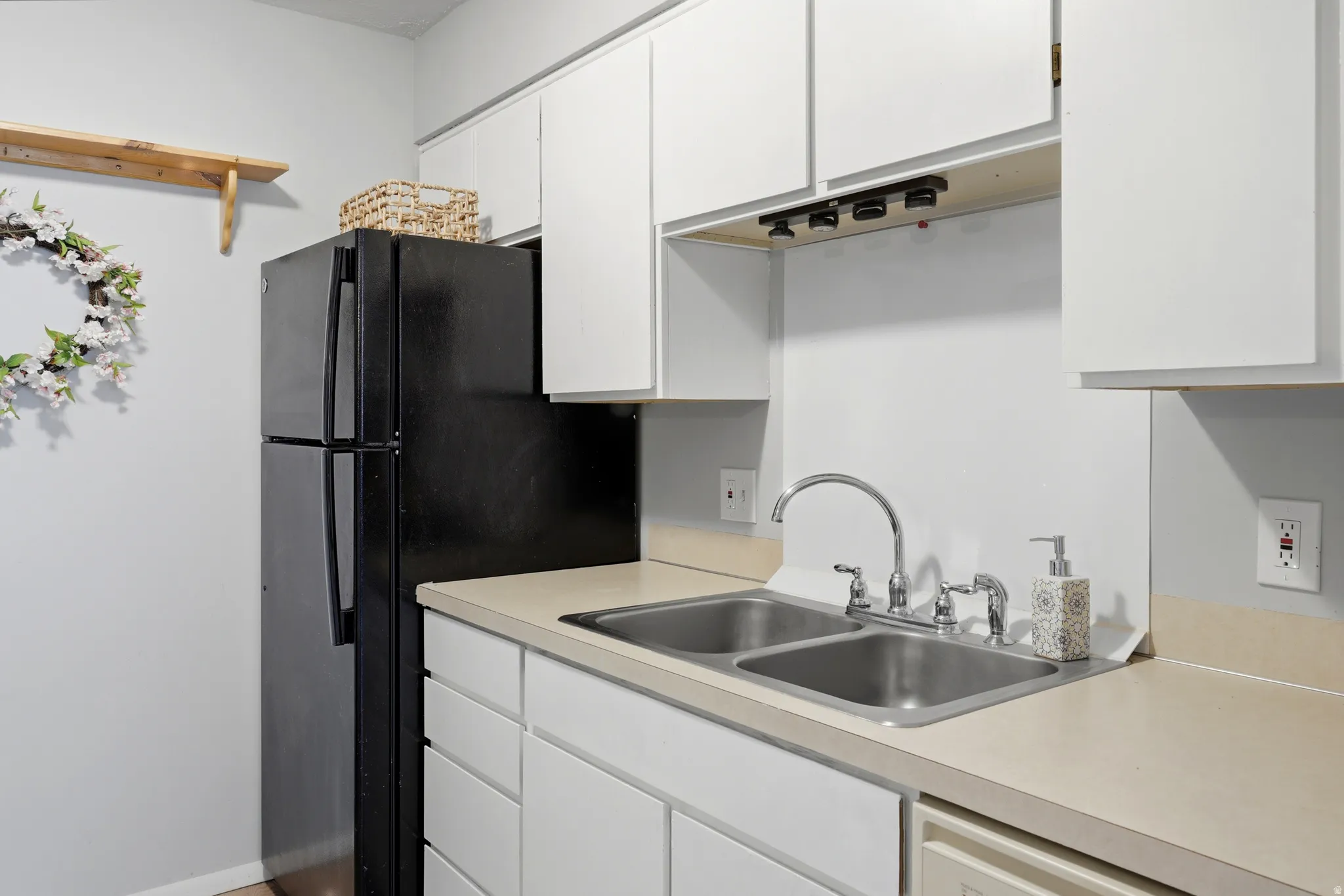 Kitchen area featuring white cabinetry, light-toned countertops, and a dual-basin stainless steel sink with a chrome faucet
