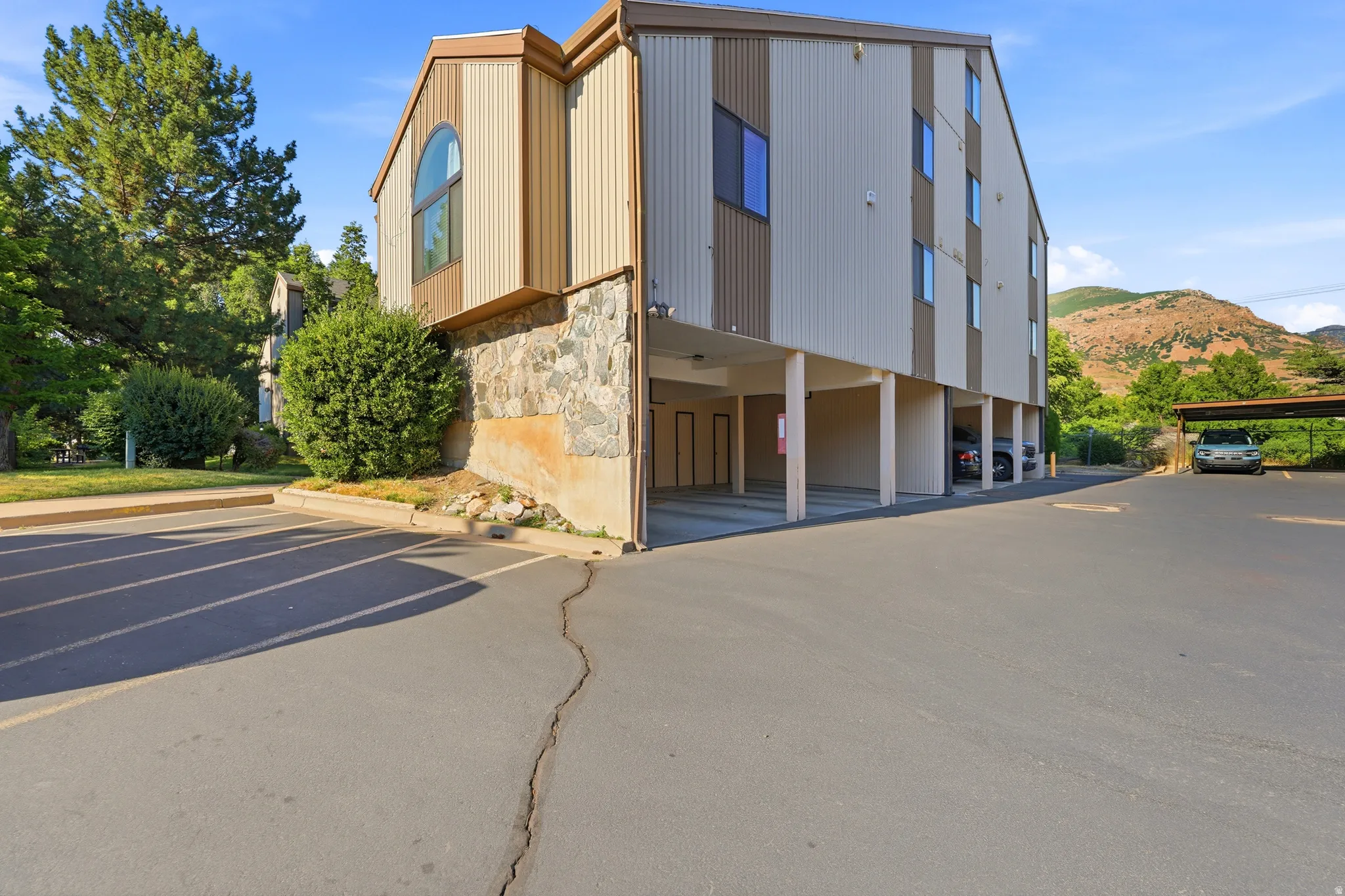 Multi-story building featuring vertical siding, a stone facade, and covered parking beneath