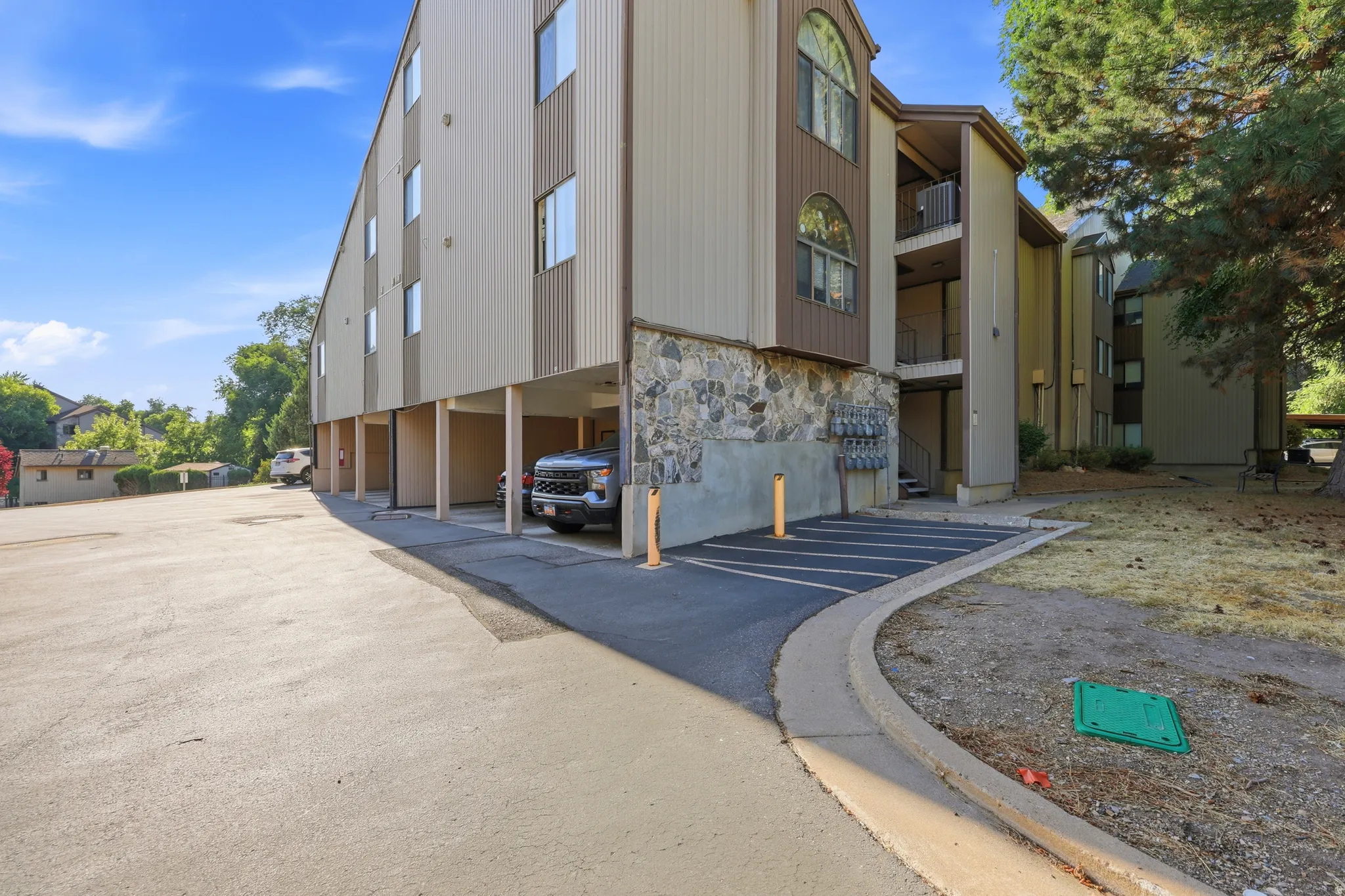 Multi-story building exterior featuring a stone facade base, vertical siding, and multiple balconies