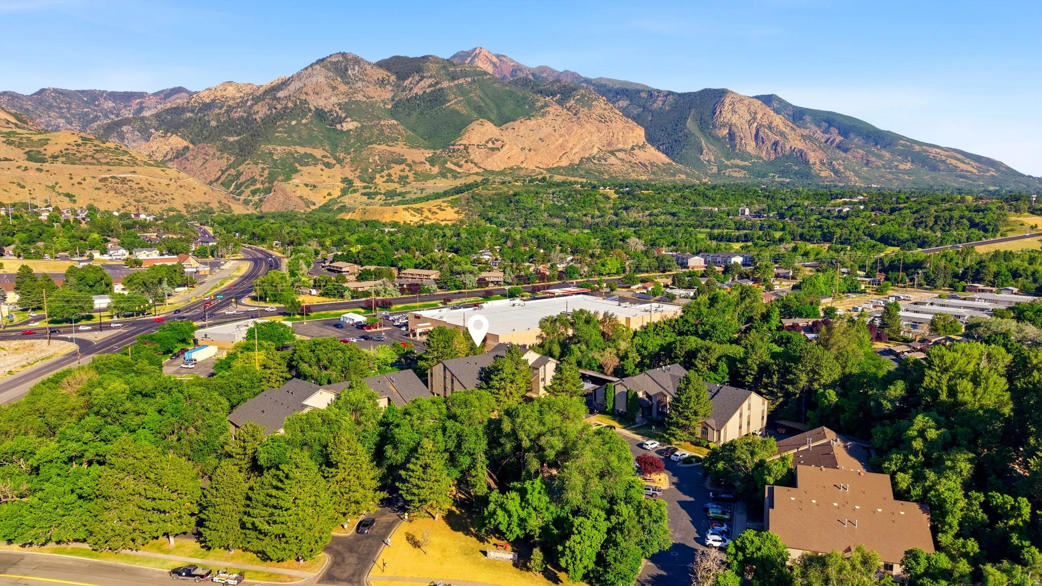 Aerial perspective showcasing a residential area nestled at the base of extensive mountain ranges