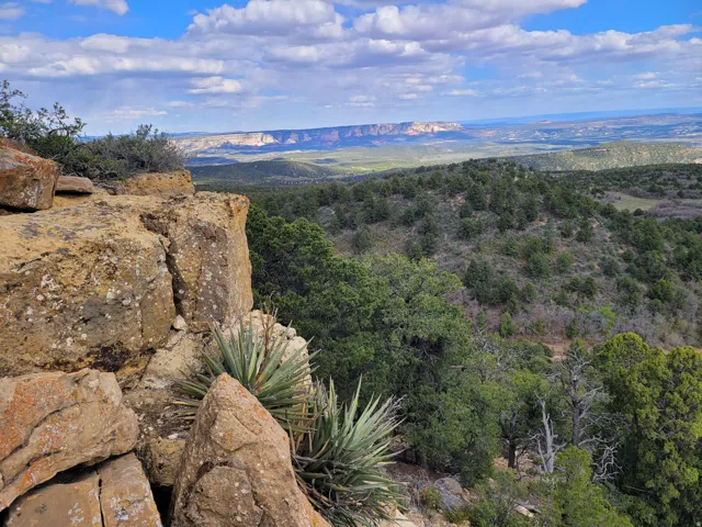 Expansive natural landscape featuring rugged rock formations and distant mesa terrain