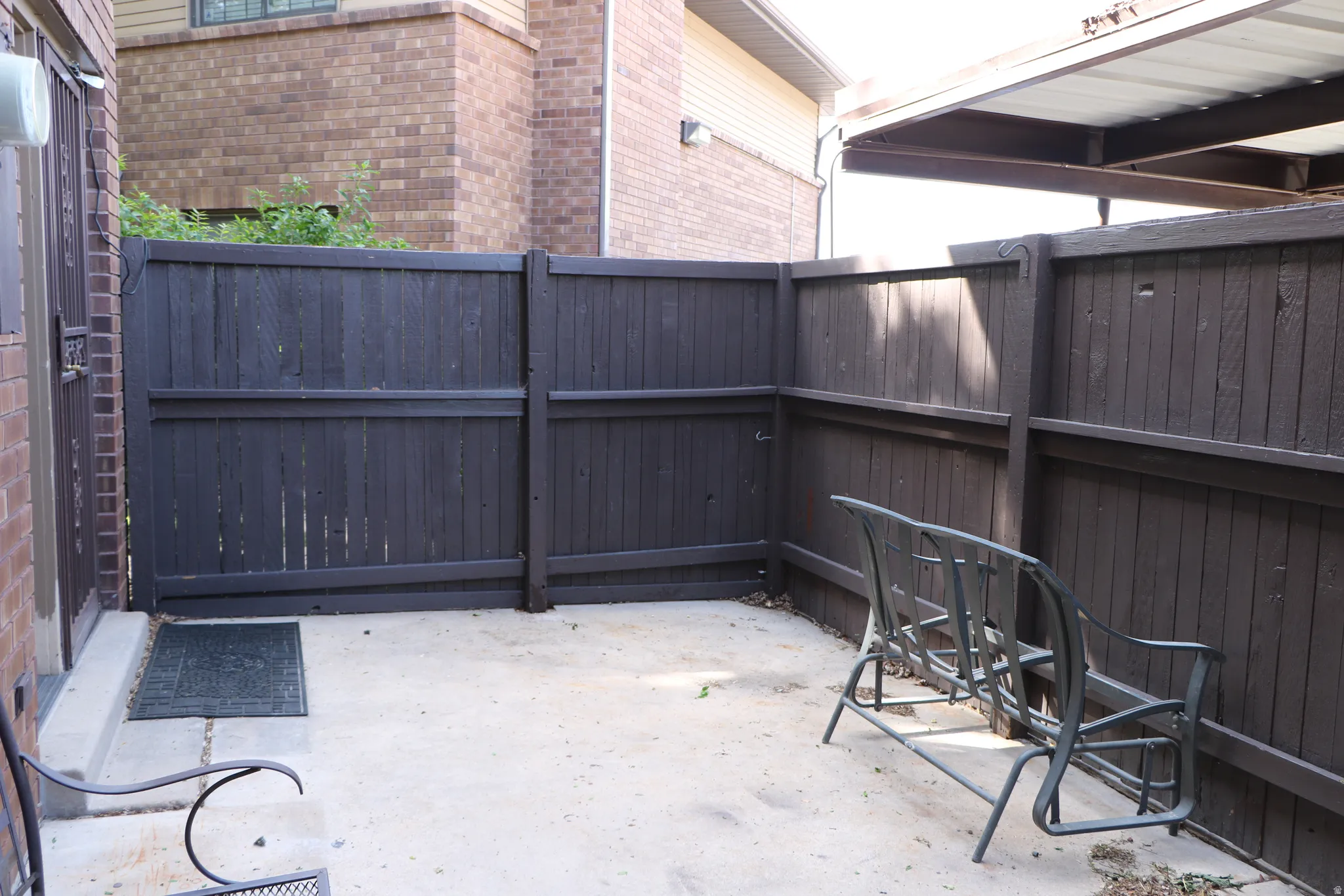 Enclosed concrete patio featuring dark-stained wood privacy fencing