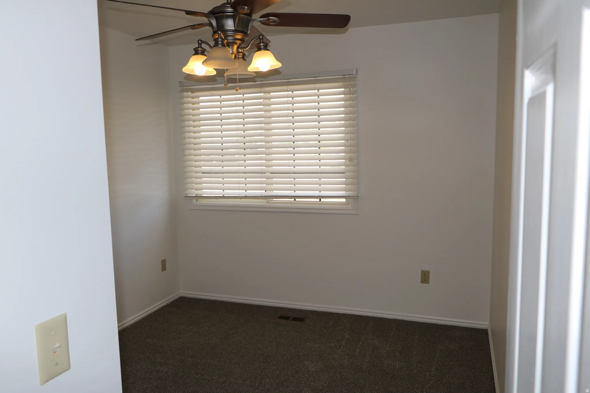 Neutral carpeted room featuring a ceiling fan with integrated lighting, a window with horizontal blinds, and white baseboards