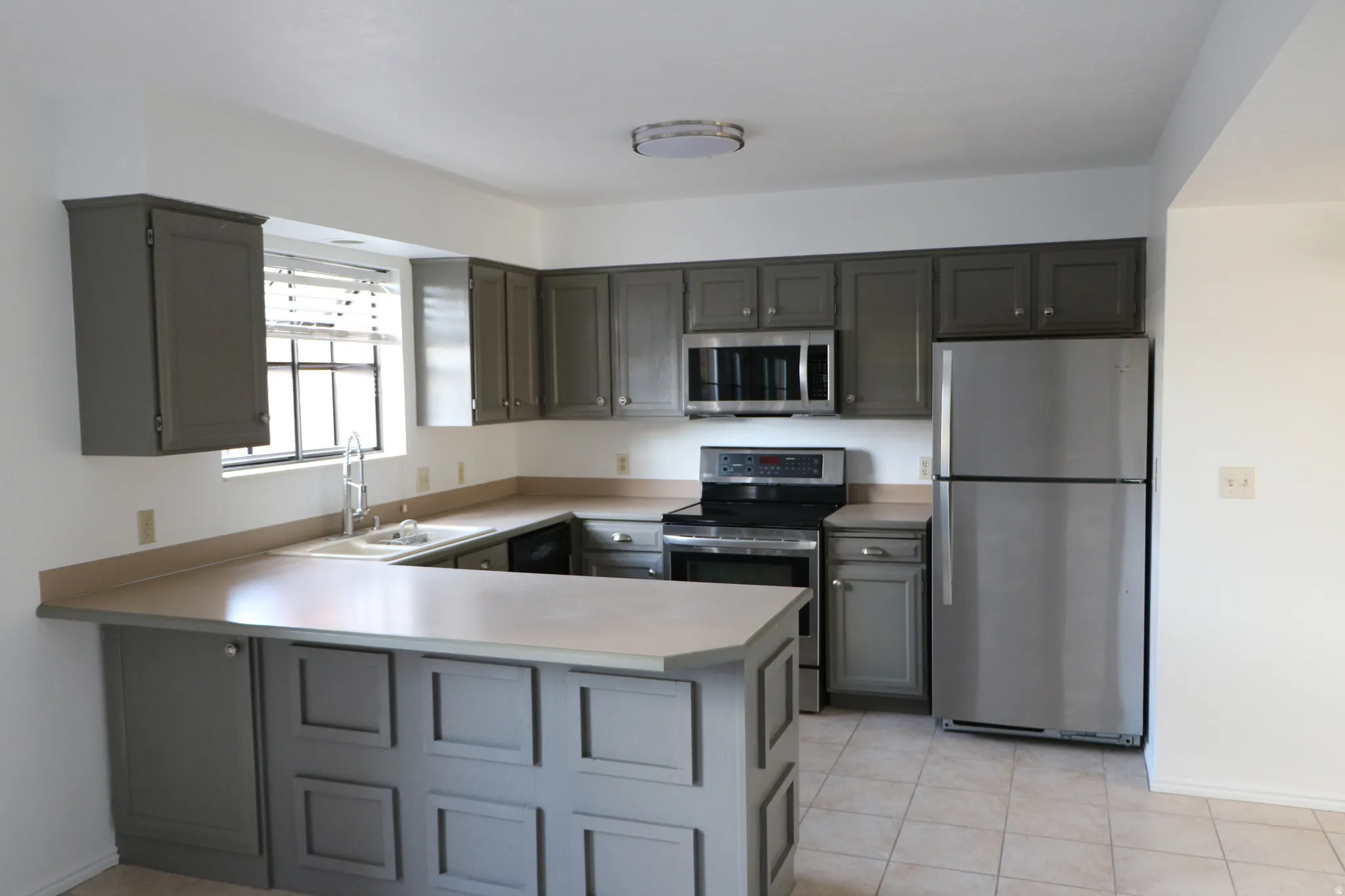 U-shaped kitchen featuring grey cabinetry, light-toned countertops, and tile flooring