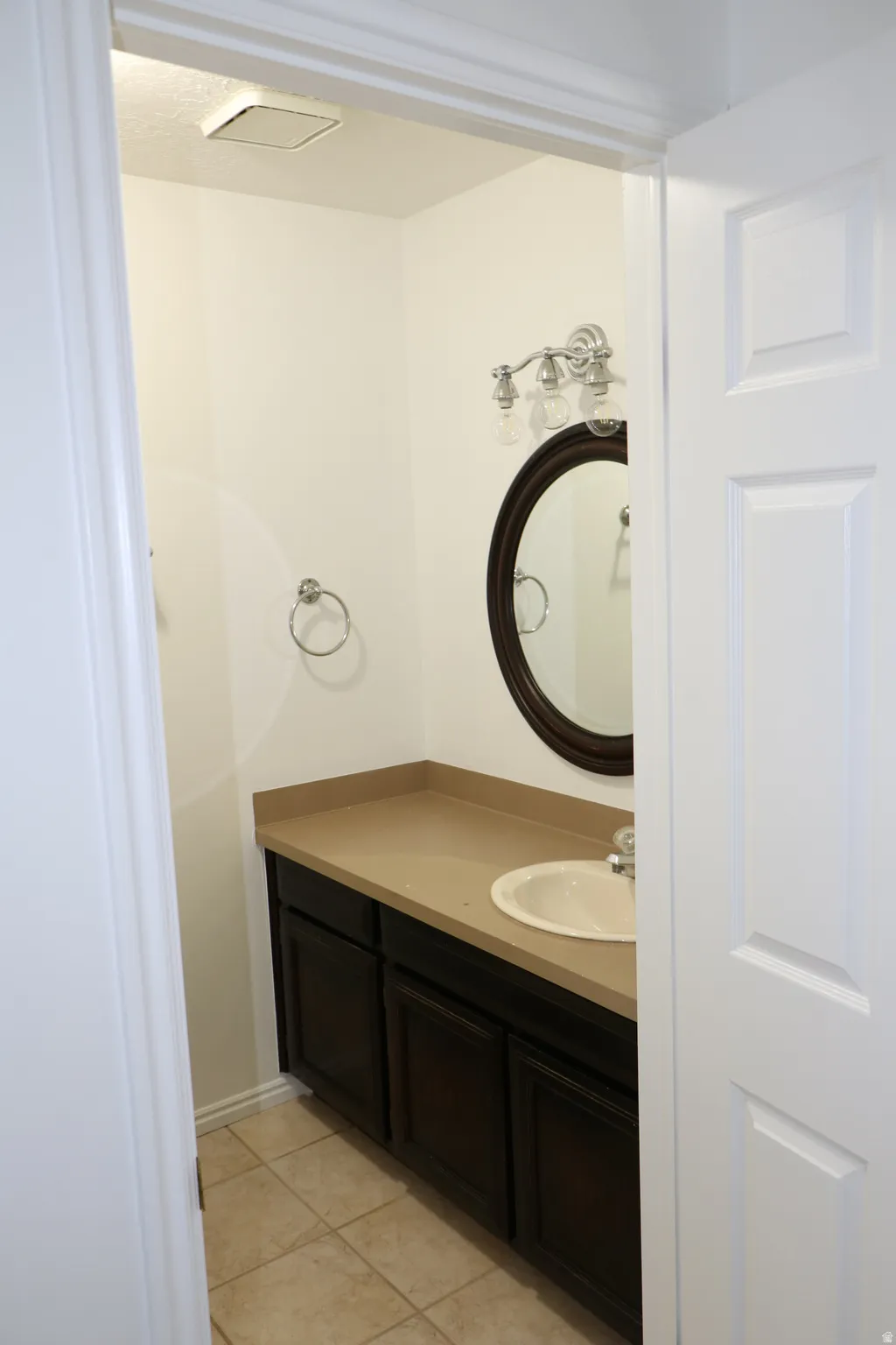 Bathroom featuring a dark wood-finish vanity with a beige countertop and an undermount sink