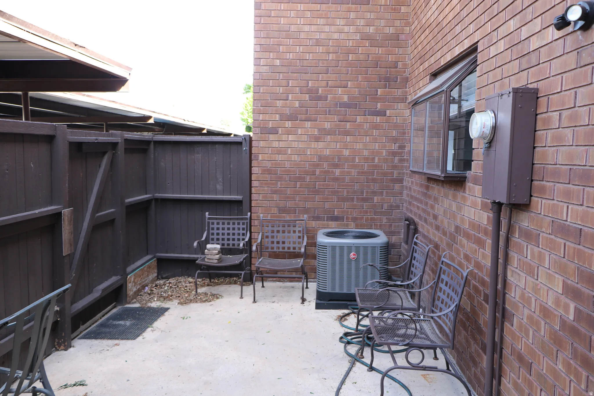 Private patio area with concrete flooring, brown brick exterior, and a privacy fence