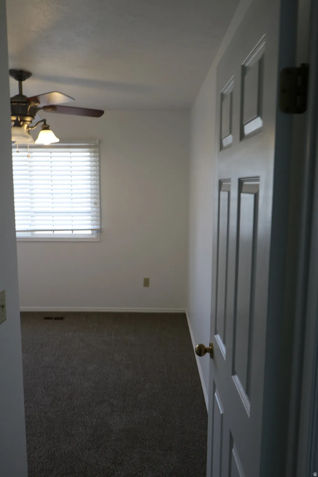 Bedroom featuring carpeted flooring, a window with blinds, and a ceiling fan with integrated lighting