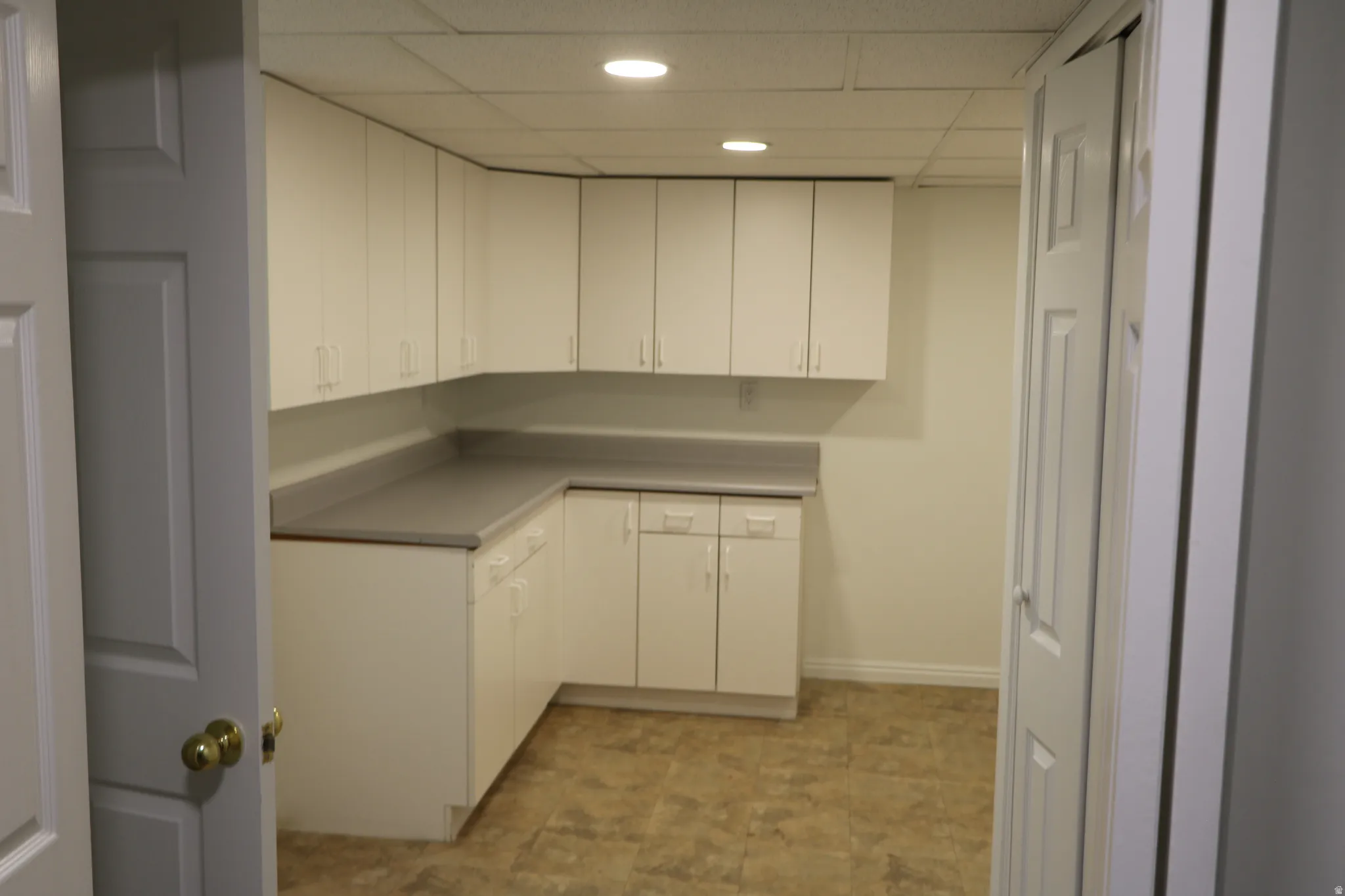 Utility room featuring extensive white cabinetry, a light gray countertop, recessed lighting, and resilient flooring
