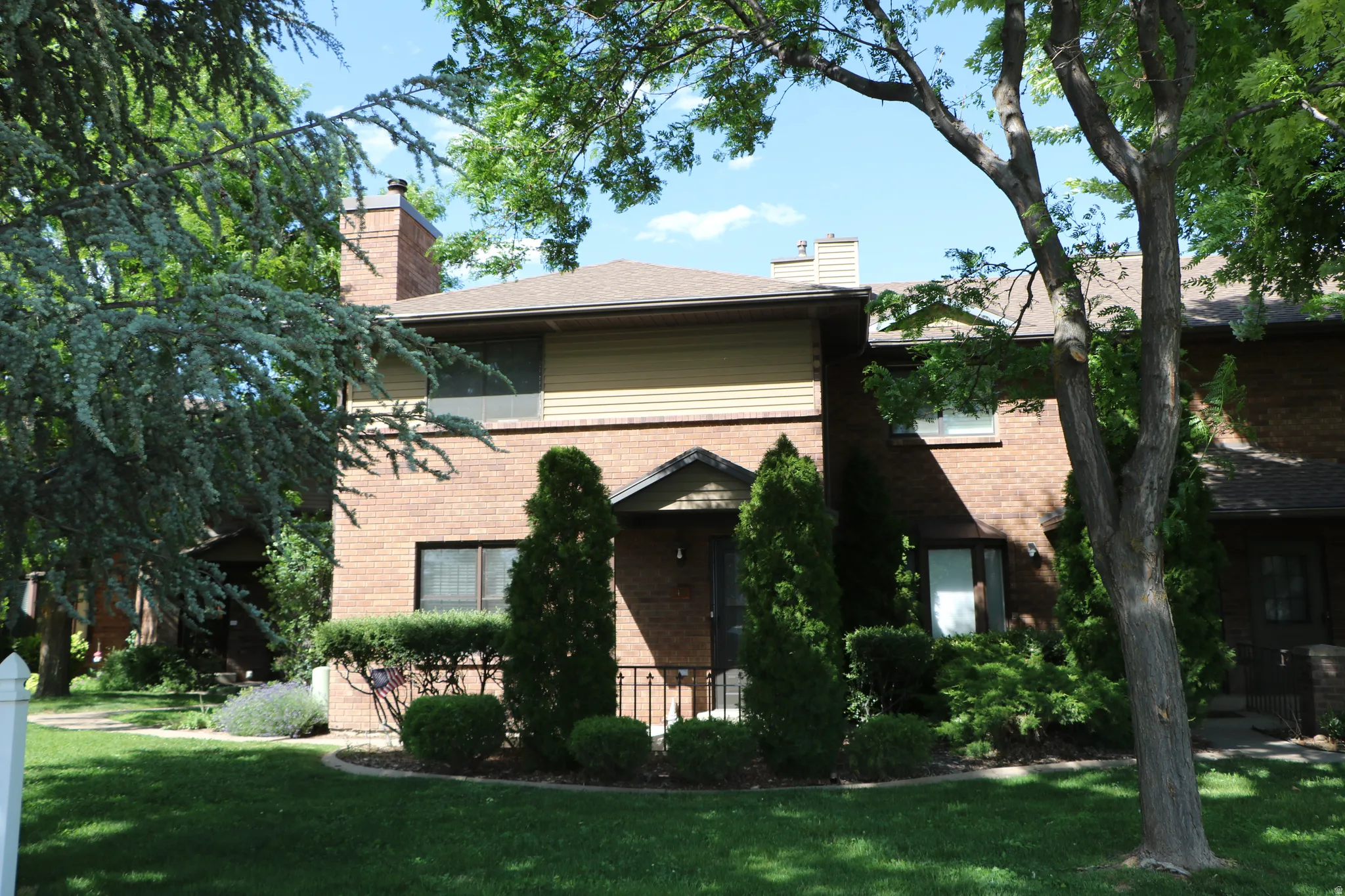Brick exterior with tan siding on the upper level, featuring an arched entryway with a black door