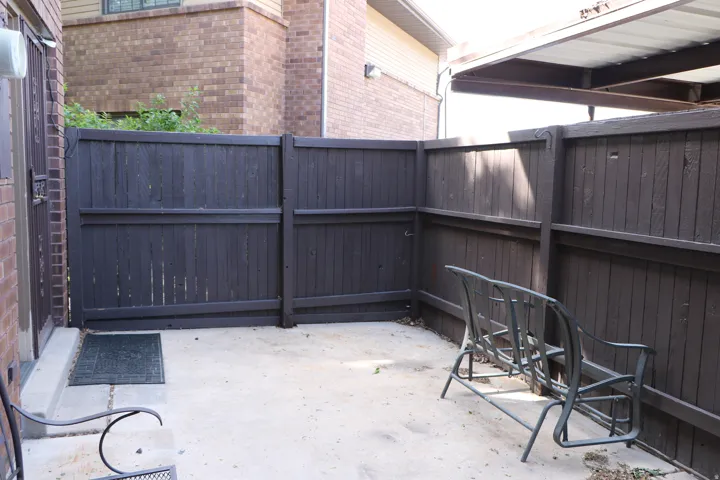 Enclosed concrete patio featuring dark-stained wood privacy fencing