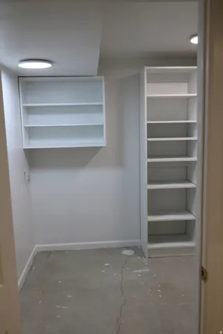 Interior storage space with integrated shelving, built-in wall cabinet, overhead recessed lighting, and painted walls