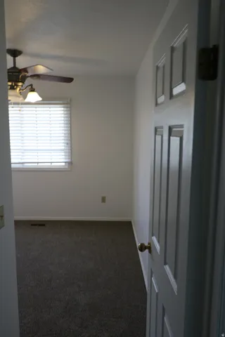 Bedroom featuring carpeted flooring, a window with blinds, and a ceiling fan with integrated lighting