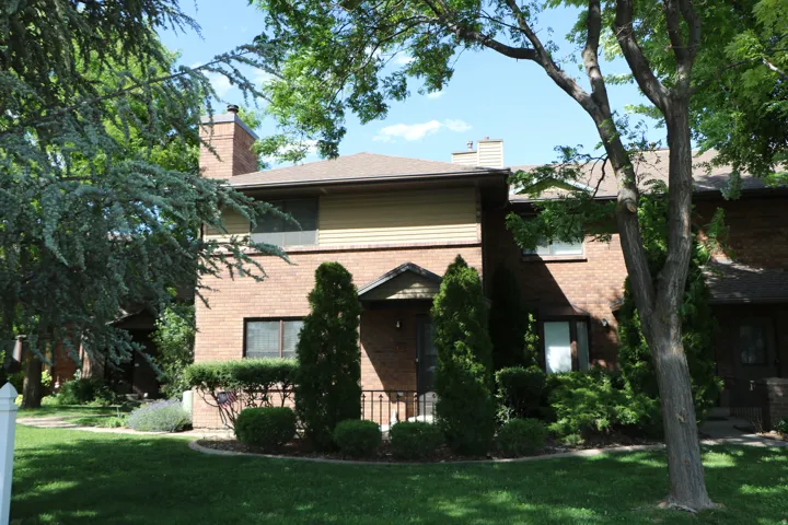 Brick exterior with tan siding on the upper level, featuring an arched entryway with a black door