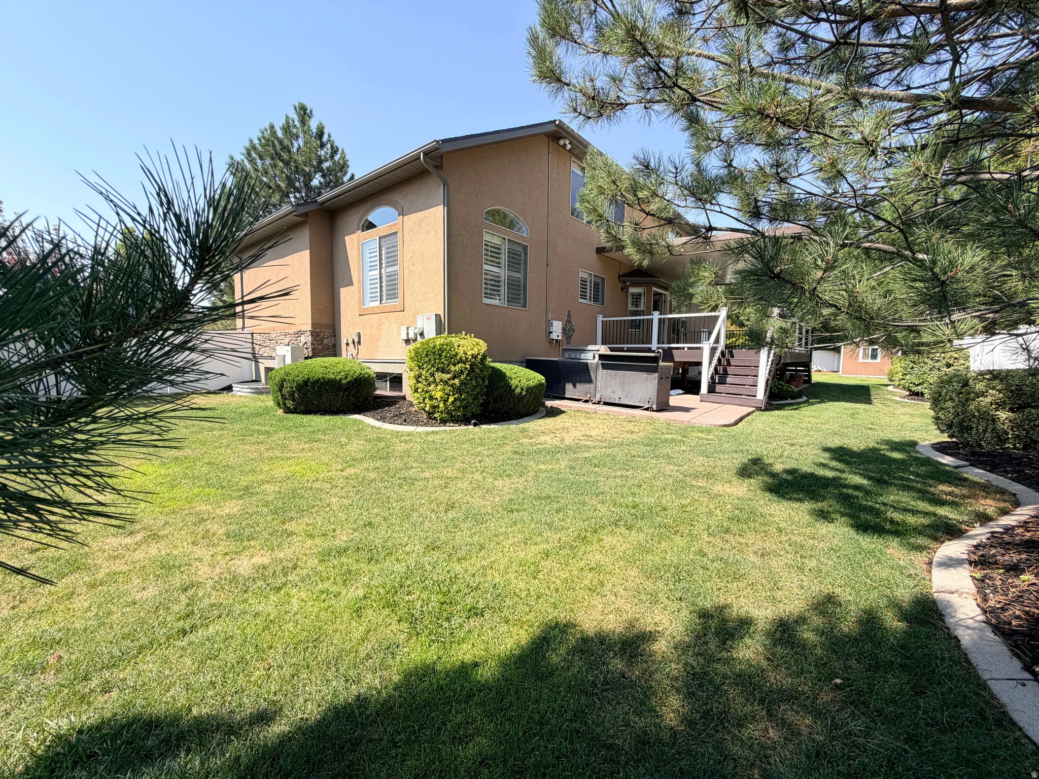 Charming stucco residence with warm tan exterior and pitched roofline, situated on expansive manicured lawn