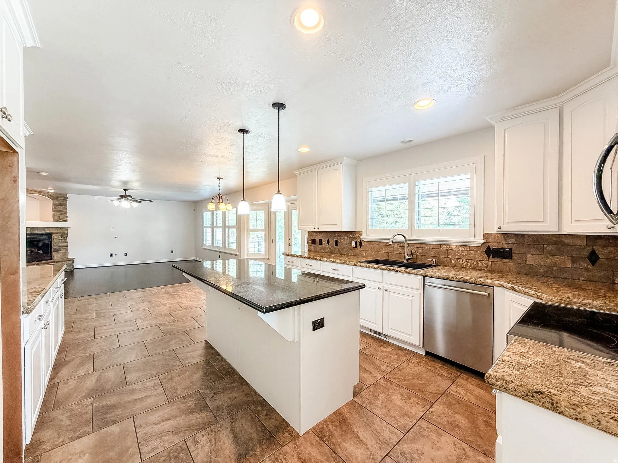 Kitchen featuring a large island, white cabinetry, integrated stainless steel appliances, and tile flooring