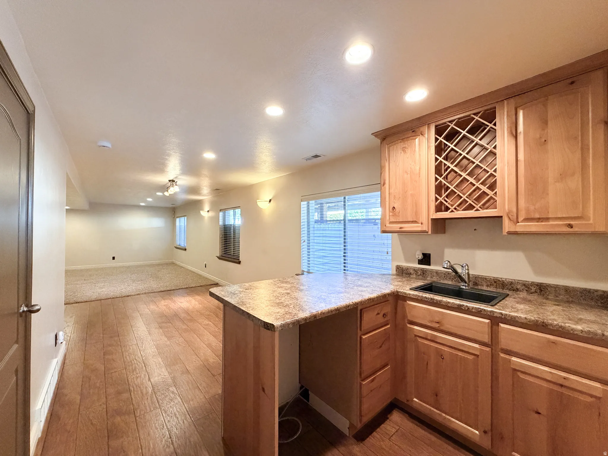 Compact wet bar with a built-in wine rack, wood-finish flooring, and recessed lighting