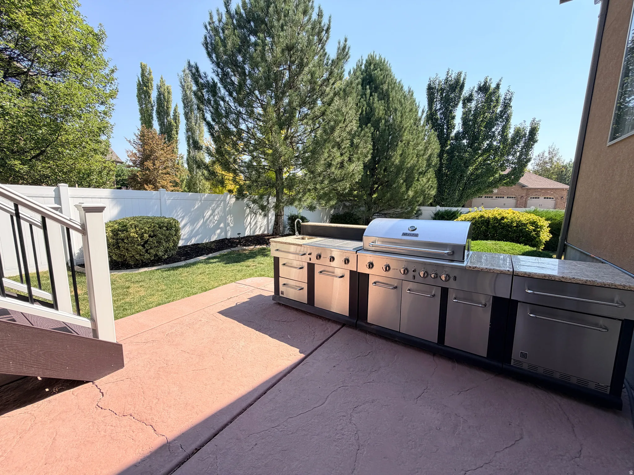 Outdoor kitchen with granite-look countertops, integrated stainless steel grill, and stainless steel cabinetry