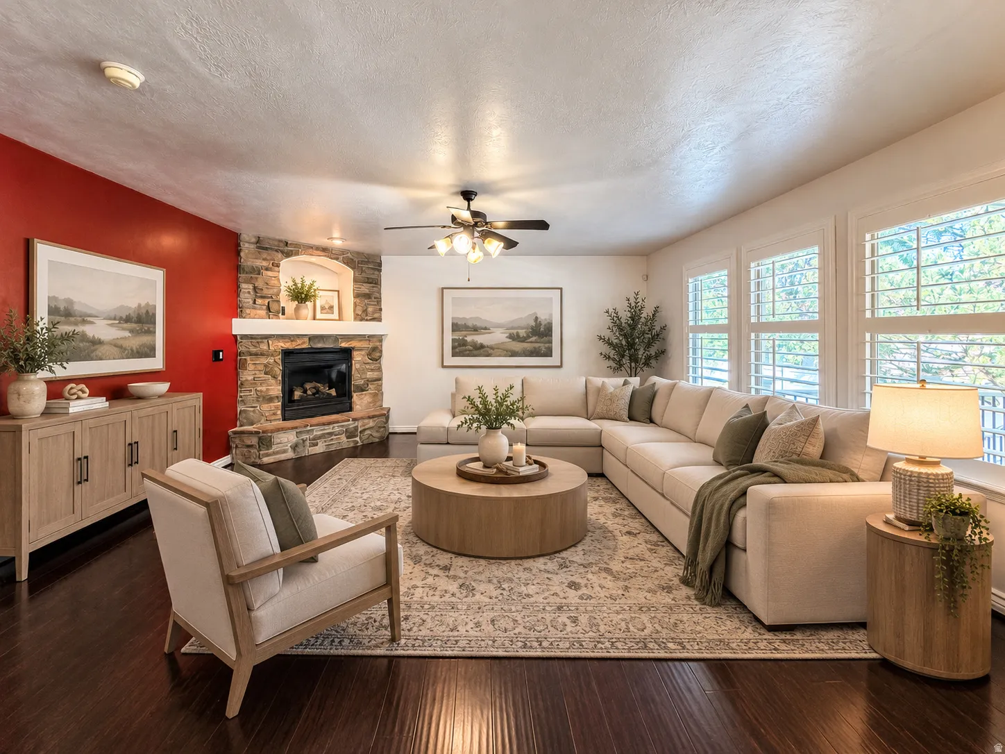 Stone-clad fireplace with hearth, dark wood-finish flooring, ceiling fan, and multiple windows with plantation shutters