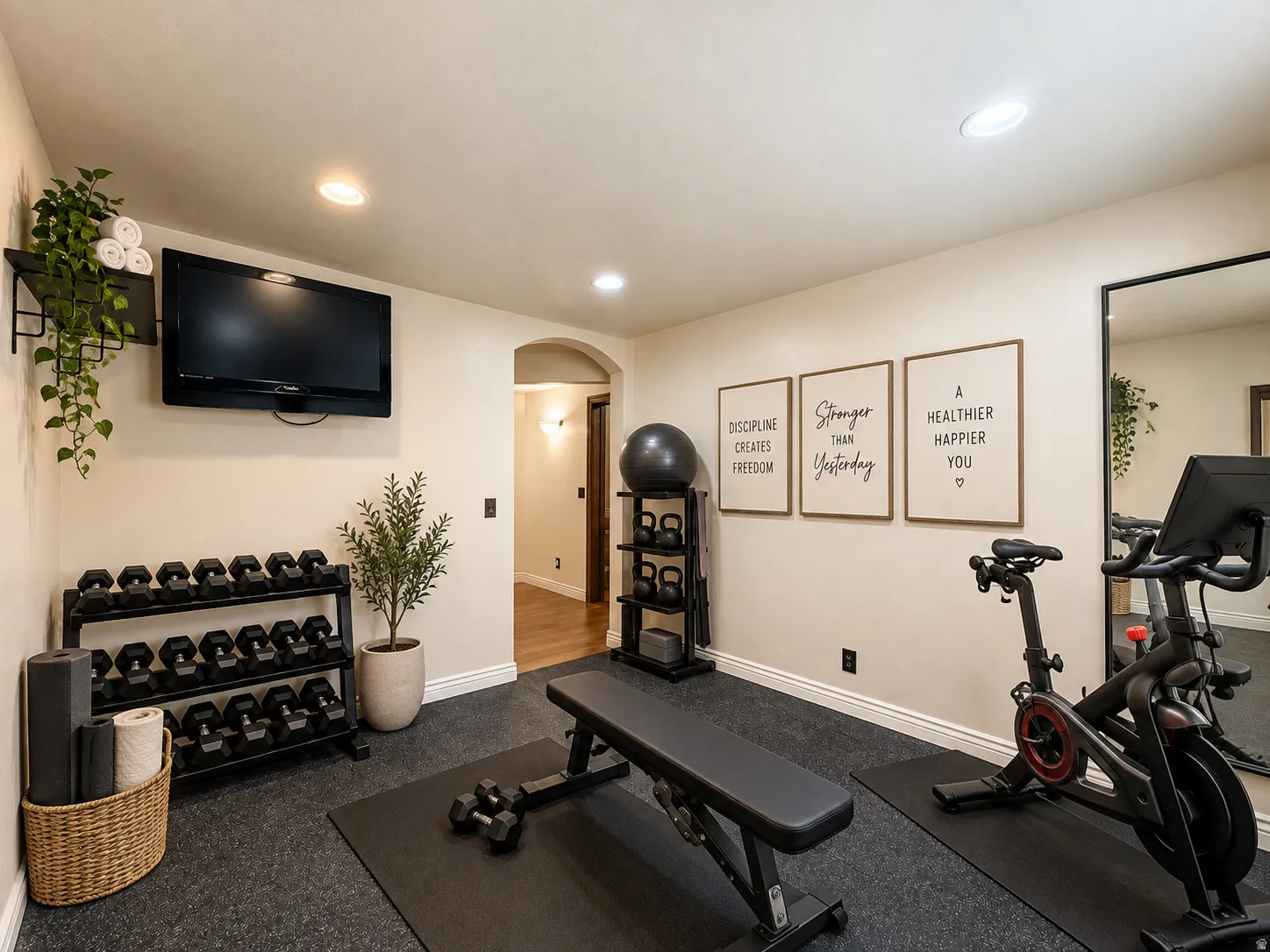 Recessed lighting illuminates the space, featuring a mounted television and a full-length wall mirror