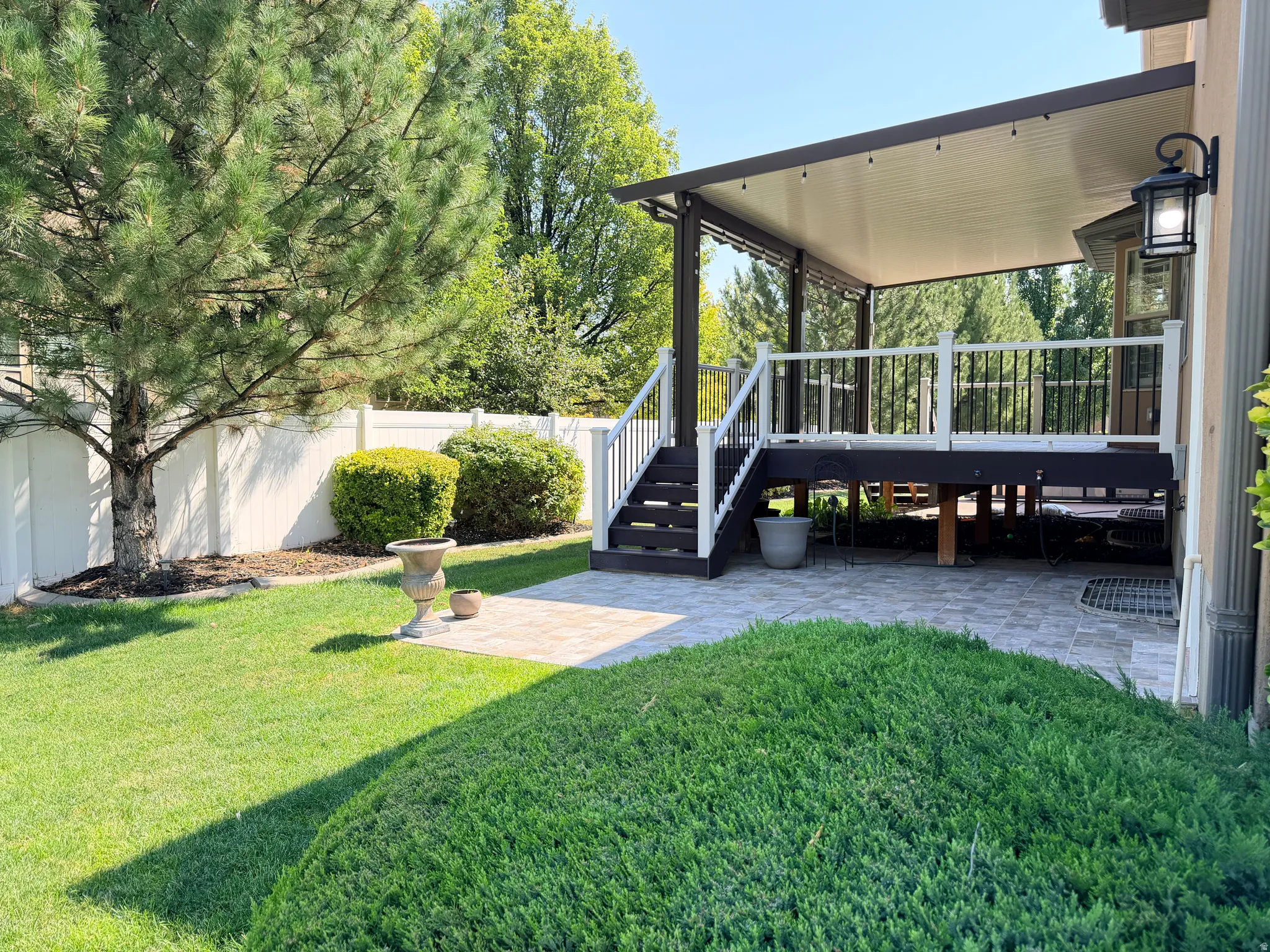 Covered outdoor deck with white railing, black balusters, and integrated lighting