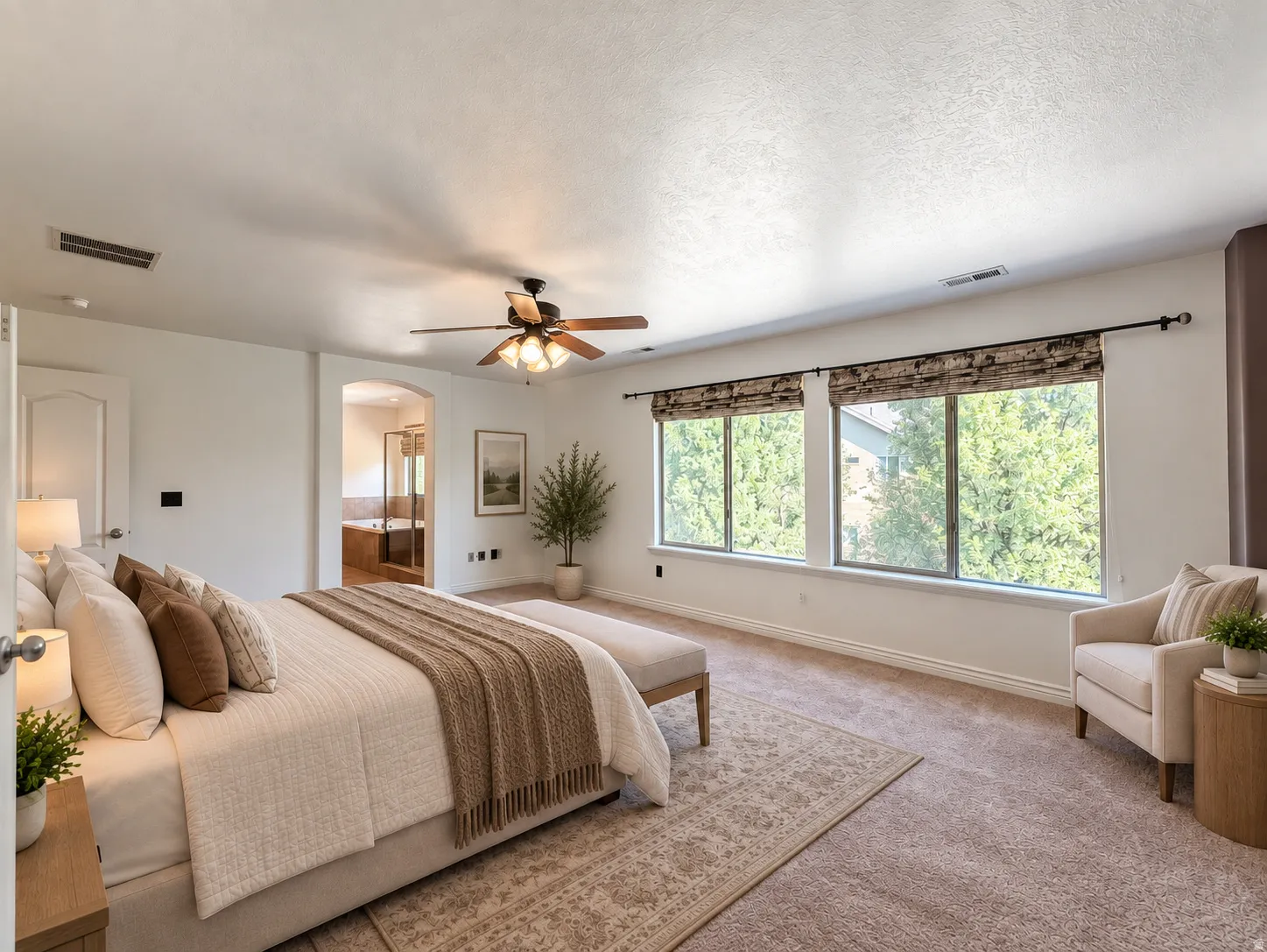 Primary suite Carpeted flooring, arched doorway, ceiling fan with light fixture, multiple windows, and roller shades