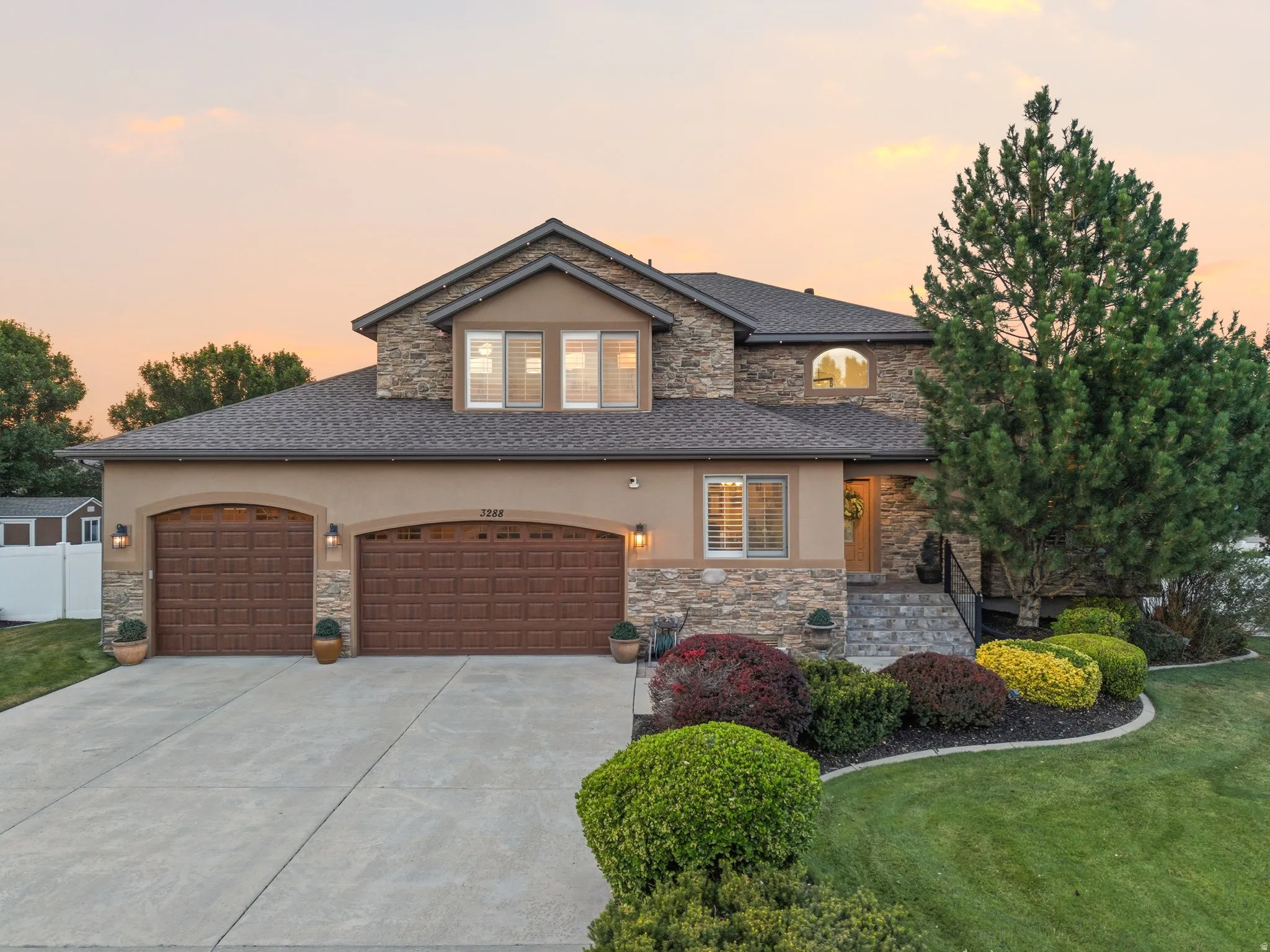 Stucco and stone facade with a two-car garage featuring arched wooden doors