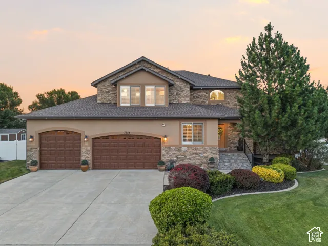 Stucco and stone facade with a two-car garage featuring arched wooden doors