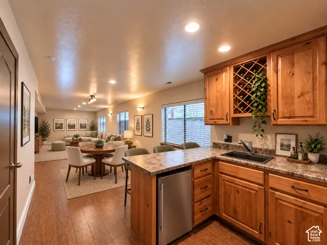 Wood-finish flooring, recessed lighting, and a built-in wet bar with a wine rack