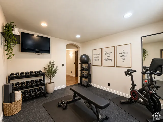 Recessed lighting illuminates the space, featuring a mounted television and a full-length wall mirror