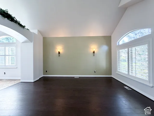 Vaulted ceilings, wood-finish flooring, arched windows with plantation shutters, and decorative wall sconces