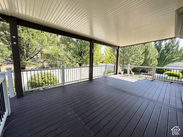 Expansive composite deck featuring dark wood-finish decking with linear board pattern, topped by a modern metal-framed pergola with integrated shade panels