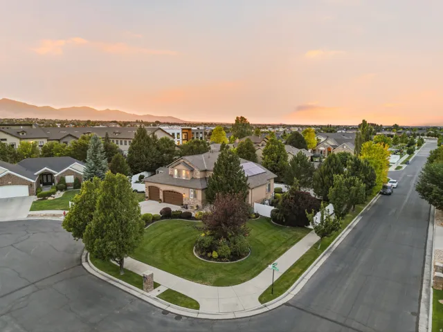 Large corner lot featuring a stucco and stone exterior, mature landscaping, a two-car garage, and solar panels