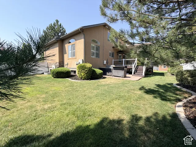 Charming stucco residence with warm tan exterior and pitched roofline, situated on expansive manicured lawn
