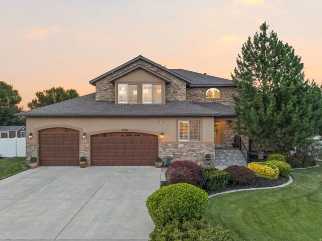 Stucco and stone facade with a two-car garage featuring arched wooden doors