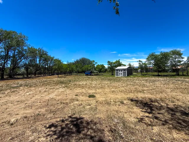 Expansive open lot featuring a detached storage shed with a gable roof and double doors