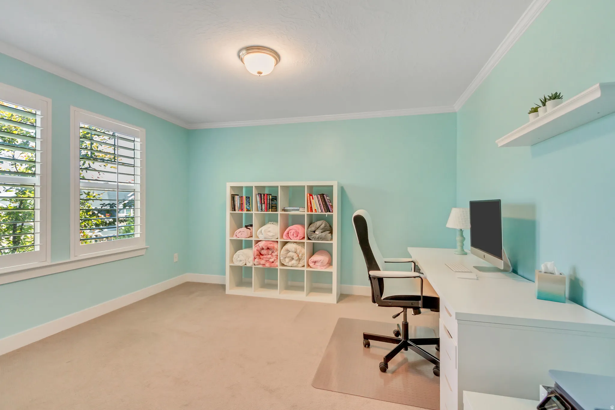 Room featuring two windows with white plantation shutters, crown molding, and light-colored carpeting