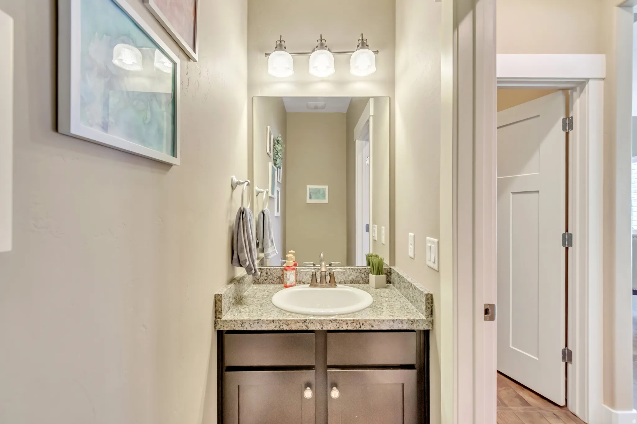 Vanity area featuring a granite-finish countertop, undermount sink, and brushed nickel faucet