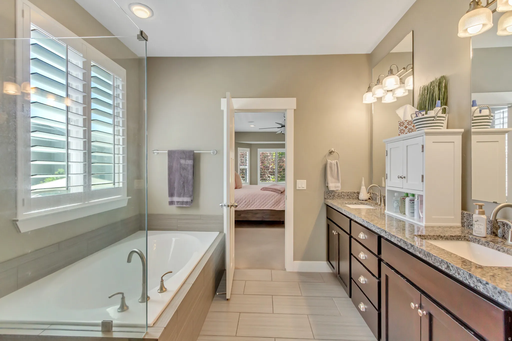 Bathroom featuring an elongated soaking tub with chrome fixtures, a clear glass shower enclosure, and white plantation shutters on the window
