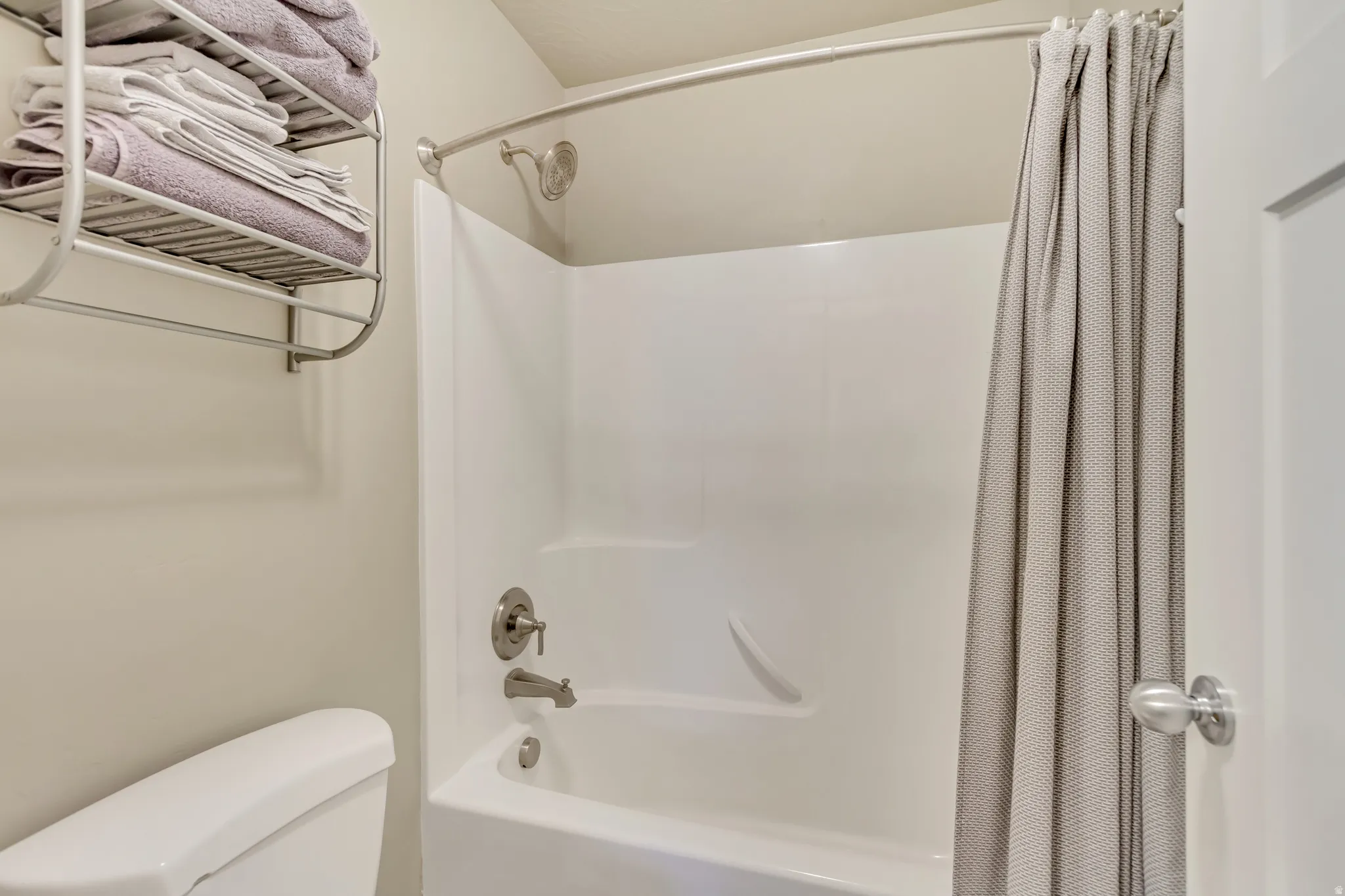White bathtub and shower combination with brushed nickel fixtures