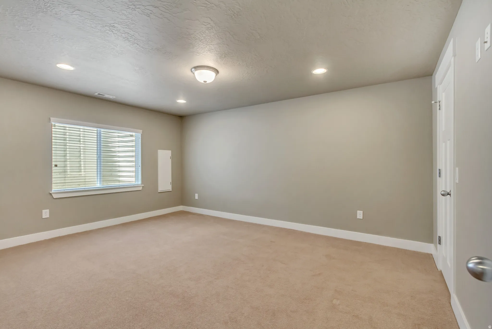 Spacious room featuring neutral carpeting, light neutral wall paint, and white trim