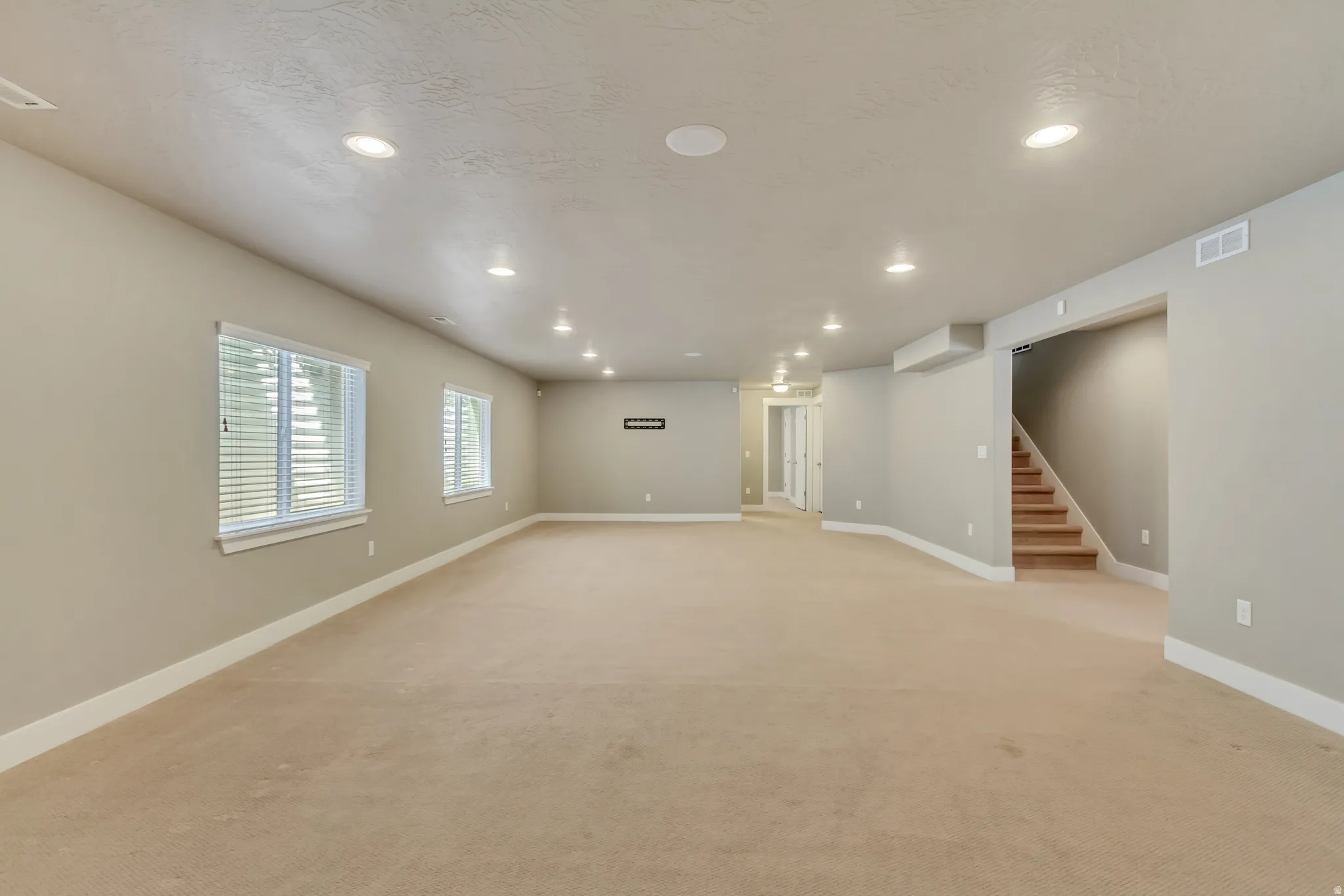 Spacious room featuring neutral paint, recessed lighting, and beige carpeting
