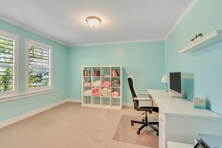 Room featuring two windows with white plantation shutters, crown molding, and light-colored carpeting