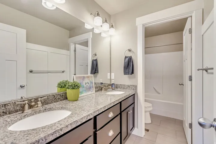 Bathroom featuring a double vanity with granite-style countertops, under-mount sinks, and dark wood-finish cabinetry